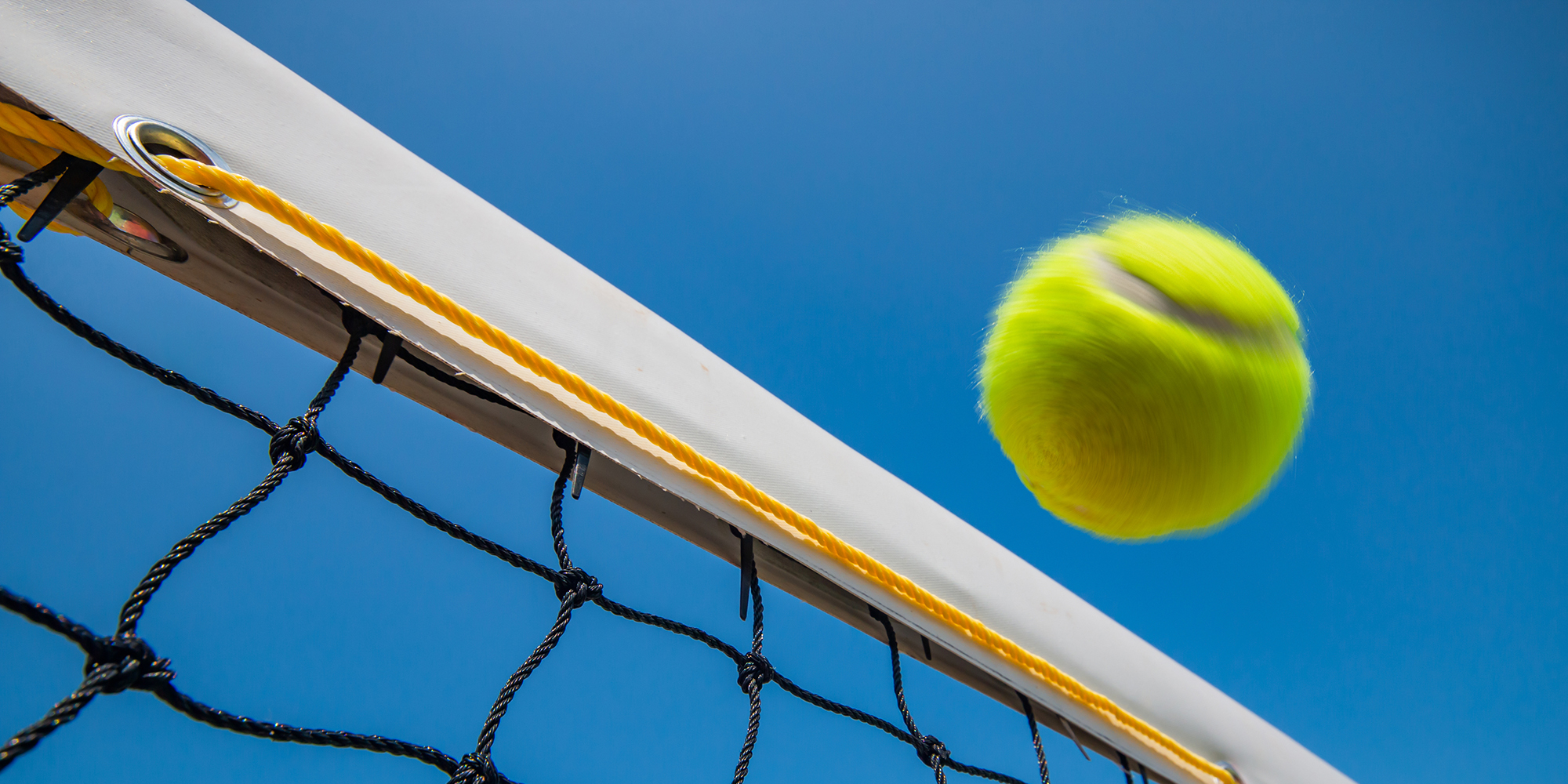 tennis ball flying over net